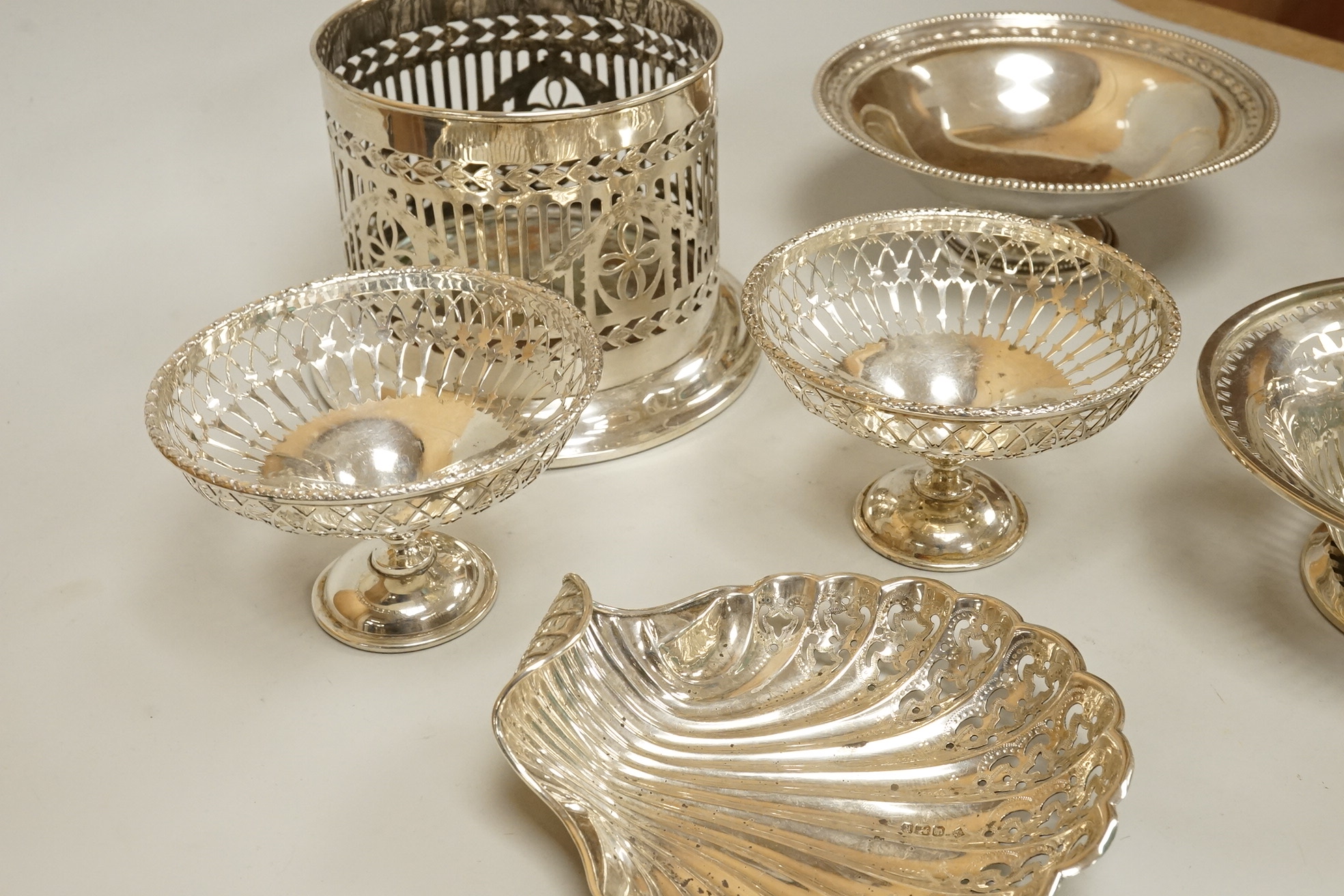 Two pairs of early 20th century silver bonbon dishes, including smallest by Mappin & Webb, Birmingham, 1913, height 6cm, together with an Edwardian silver butter shell and a pair of Edwardian silver mounted bottle coaste